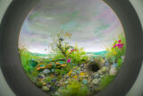 A round "portal" gives a glimpse into a diorama of plants and fungi under a gray sky