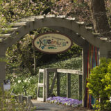 A gateway in a garden reading "Adventure Garden"
